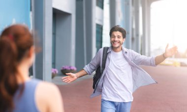 Eşi kocasını havaalanı terminalinde karşılıyor, evine hoş geldin diyor. Sarılmak için kollarını açan adam