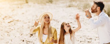 Aile pikniği. Kızı ile ebeveynler sabun kabarcıkları üfleme, doğada dinlenme olan