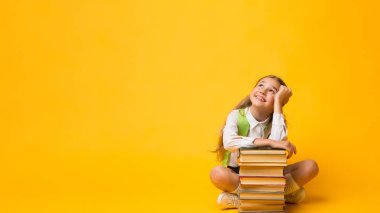 Okula geri dön. Liseli Kız Sırt çantasıyla Sırt Sırtında Otururken Sarı Stüdyo Arkaplanının Üzerinde Poz Veriyor. Panorama, Boşluğu Kopyala