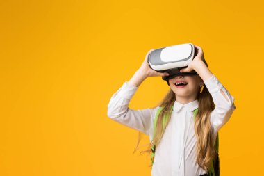 Eğitim Geleceği. Heyecanlı Öğrenci Kız Sarı Arkaplanda Sanal Gerçeklik Deneyimi VR kulaklığı kullanıyor. Stüdyo Çekimi