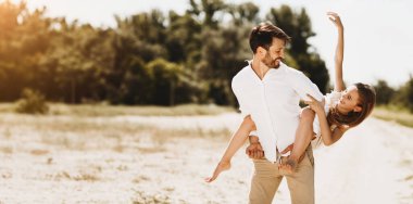 Karantina Sonrası Yaz. Ebeveynler ve kızları karantinadan sonra güneşli bir günde dışarıda birlikte eğleniyorlar. Baba çocuğu taşıyor ve gülüyor..