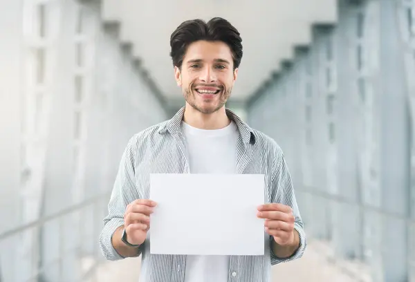 stock image Meeting arrivals. Friendly millennial man holding name board at airport, empty space for you text