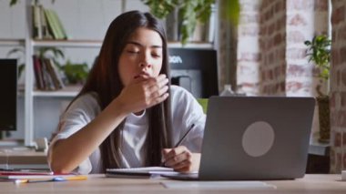 Sıkıcı uzaktan öğrenme. Asyalı öğrenci kız esniyor, dizüstü bilgisayarda Webinar izlerken uyuyakalıyor.