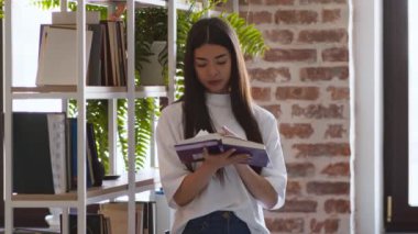 Kişisel gelişim. Genç Asyalı kız kafedeki kitaplıkta yeni kitap okuyor.