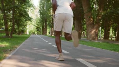 Aktif siyah adam boş sabah parkında koşuyor, kardiyo çalışması, arka görüş, ağır çekim