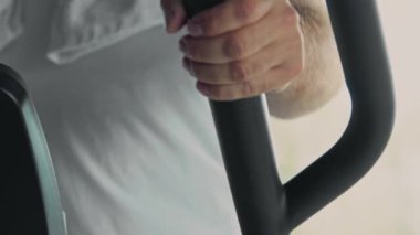 Spor salonundaki sporcunun eliptik antrenör üzerinde egzersiz yaparken yakın çekim, yavaş çekim.