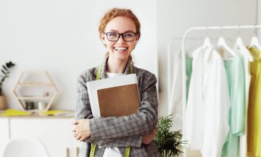 Kendine güvenen Terzi. Masaya yaslanmış, eskiz defteri, dikey resim, tam boy.