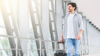 Havaalanı yürüyüşü. Terminalde yürüyen, bavullu yakışıklı genç adam, biniş kapısına gidiyor.