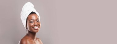 Banyodan sonra. Gri arka planda beyaz havluyla gülümseyen güzel Afro-Amerikan kadın portresi.
