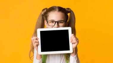 Uzaktan eğitim. Liseli Kız, Sarı Stüdyo Arkaplan Üzerine Boş Ekran Pozu Veren Dijital Tablet Tutuyor. Model