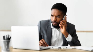 Endişeli işadamı cep telefonu konuşuyor ve dizüstü ekran bakarak, onun bilgisayar, panorama ile sorunu çözmek için teknik desteğe ulaşmaya çalışıyor