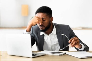 Çok çalışan Afrikalı Amerikalı çalışanın ofiste zor bir günün ardından gözlüklerini çıkarması, boşluğu kopyalaması.