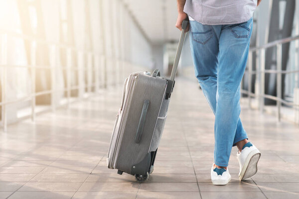 Searching For Gate. Unrecognizable Man Standing With Hand Luggage Suitcase In Airport Terminal, Cropped Image, Rear View