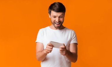 Mobil Oyun. Bağımlı Adam Sarı Stüdyo Arka Plan Üzerinde Smartphone Oyun Oynuyor. Kopyalama Alanı