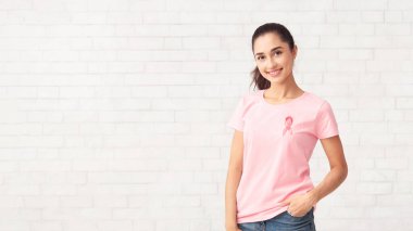 Göğüs kanseri desteği. Beyaz Tuğla Duvarı 'nın üzerinde kameraya gülümseyen kurdeleli gönüllü kız. Boşluğu Kopyala