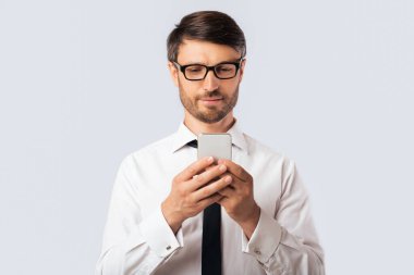 İş Uygulaması. Ciddi İşadamı Beyaz Stüdyo Arkaplanının Üzerinde Duran Akıllı Telefon Kullanıyor. Boşluğu Kopyala