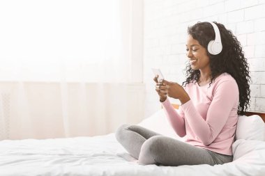 Gülümseyen siyah bayan yatakta oturuyor, arkadaşlarıyla sohbet ediyor ve müzik dinliyor, mekanı kopyalıyor.