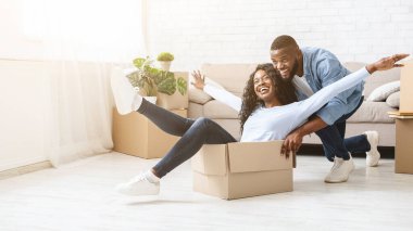 Genç Afrikalı adam içinde onun kadın ile ambalaj kutusu iterek, yeni bir evde hareket ederken eğlenmek, kopya alanı ile panorama