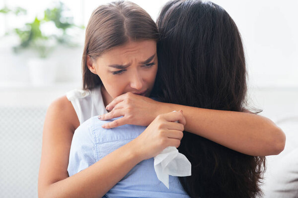 Supportive Woman Hugging Depressed Friend Comforting Her After Break Up With Ex Sitting On Sofa At Home. Selective Focus