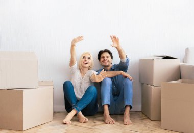 Daireyi taşıyorum. Karı koca yerde oturup yeni ev için iç tasarım hakkında konuşuyorlar. Boş Alan