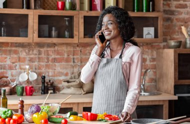 Sağlıklı akşam yemeği pişirirken akıllı telefonda keyifli sohbet ler alan afrikalı genç kadın, kopya alanı