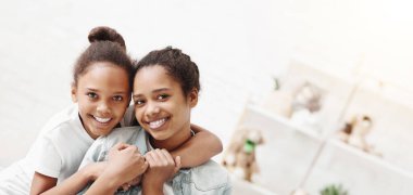 Evde birbirlerine sarılarak iki sevimli Afro-Amerikan kız kardeş
