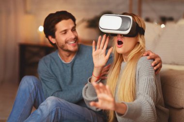 Heyecanlı eşler sanal gerçekliği deneyimlemek ve evde eğlenmek için VR kulaklık kullanıyor. Modern Ev Eğlencesi.