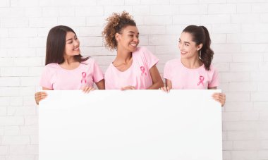 Üç Çok ırklı Kızlar Pembe Meme Kanseri T-Shirt Tuğla Duvara Karşı Boş Beyaz Tahta Holding. Mockup