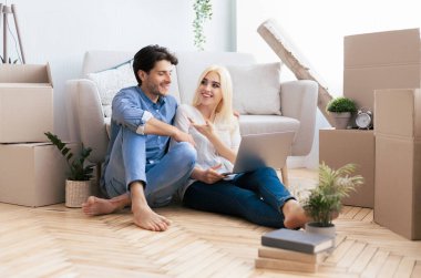 Taşındıktan sonra dizüstü bilgisayarlı çift New Flat House 'da yerde dinleniyor. Boşluğu Kopyala