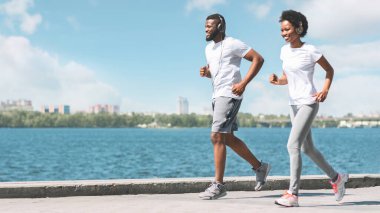 Sabah egzersizi. Neşeli Afrikalı Amerikalı Çift Şehirde River Embankment boyunca Jogging. Panorama, Boş Alan