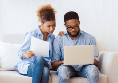 Ciddi Afrika kökenli Amerikalı eşler taşındıktan sonra dizüstü bilgisayar okuyarak koltukta oturuyorlar. Ev Alma Sorunu