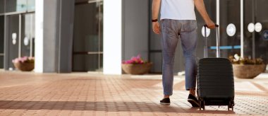 Tatil Zamanı Konsepti. Beyaz bir adam bavul taşıyor ve havaalanı terminaline doğru yürüyor.