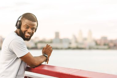 Gülümseyen Siyah Adam Köprüde Dinleniyor, müzik dinliyor ve manzaranın tadını çıkarıyor, boşluk