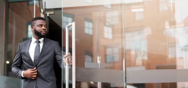 Yakışıklı kendine güvenen Afrikalı işadamı resmi takım elbise modern ofis merkezinden dışarı yürüyüş, kopya alanı