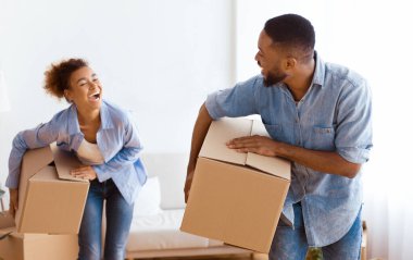 Paketli taşınma kutuları taşıyan ve yeni daireye gülen Afrikalı Amerikalı çift. Seçici Odaklanma