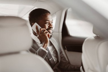 Takım elbiseli siyah bir işadamı arabanın arka koltuğunda oturur ve cep telefonuyla konuşur. Gülümsüyor ve sohbetten hoşlanıyor gibi görünüyor. Arabaların içi temiz ve modern..