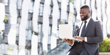 Şehirdeki kahve molası sırasında bilgisayarlı bilgisayarı kullanan gülümseyen siyahi iş adamı. Boş Boşluk