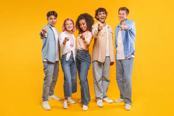 stock image Five young adults stand in a line, pointing their index fingers toward the camera. They all smile at the camera, exuding a sense of camaraderie and unity.