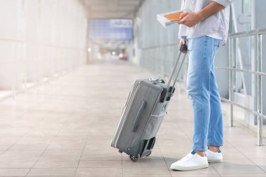 Hafta sonu gezisi. Pasaportu, haritası ve bavulu olan tanınmayan bir adam havaalanı terminalinde duruyor, biniş saatini, kesilmiş resmi ve boş alanı bekliyor.
