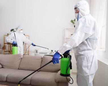 Coronavirus dezenfeksiyonu. Tehlikeli maddeler kullanan insanlar dezenfekte yapıyor. Fotokopi odası, sıcak buhar temizleme.