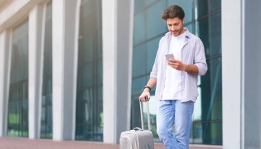 Online Taksi Uygulaması Konsepti. Akıllı Telefonlu Genç Adam Havalimanı 'nın yanında duruyor, Nakil Arabası siparişi veriyor,