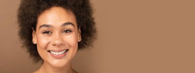 Binlerce yıllık neşeli Afro-Amerikan kıvırcık saçlı çıplak makyajlı kadın kameraya bakıyor, kahverengi arka planda, stüdyoda izole edilmiş, yakın plan, kopyalama alanı