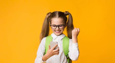 Okul Uygulaması. Neşeli Öğrenci Cep Telefonu Jesti Evet Sınavı Çevrimiçi Sarı Stüdyo Arkaplanı Üzerinde Geçiyor.