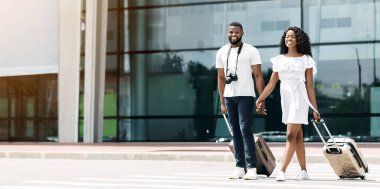 Gülümseyen siyah bir çift havaalanı binasının önünde birlikte yürür, bagajlarını arkalarından çekerler. İkisi de dört gözle bekliyor ve birlikte iyi vakit geçiriyor gibi görünüyorlar..