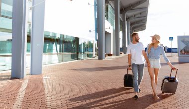 Mutlu çift havaalanı terminal binası önünde yürüyüş, bavul, boş alan çekerek