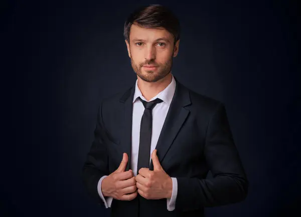 Stock image Confident Businessman Looking At Camera Holding Jacket Lapels Posing Over Black Background. Studio Shot