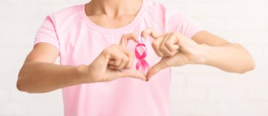 Göğüs kanseri farkındalığı. Beyaz Tuğla Duvarın Üzerindeki Pembe Kurdele Sembolü Kız El kol hareketi. Kırpılmış