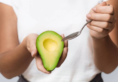 Beyaz Stüdyo Arkaplanında Kaşıkla Avokado Yiyen Tanımlanamayan Kadın. Kırpılmış, Seçici Odaklanma