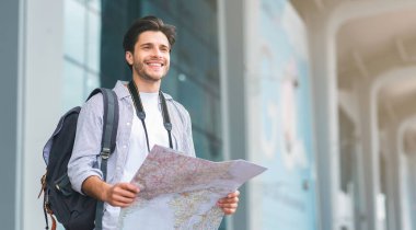 Turist adam harita üzerinde rota arıyor, havaalanında ayakta , panorama, boş alan