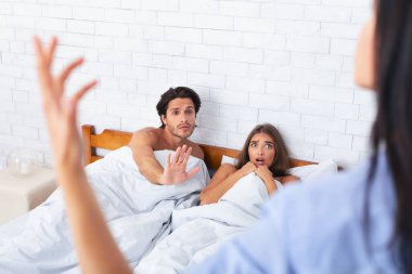 Infidelity. Girlfriend Catching Cheating Boyfriend Lying In Bed With Another Woman At Home. Selective Focus clipart